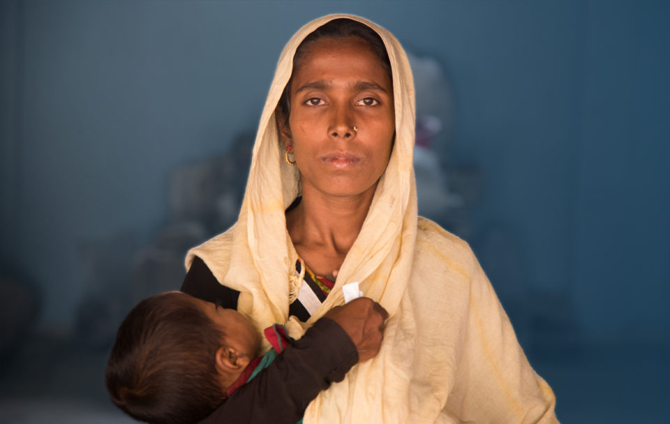 Women holding a young child, looking direct into camera.